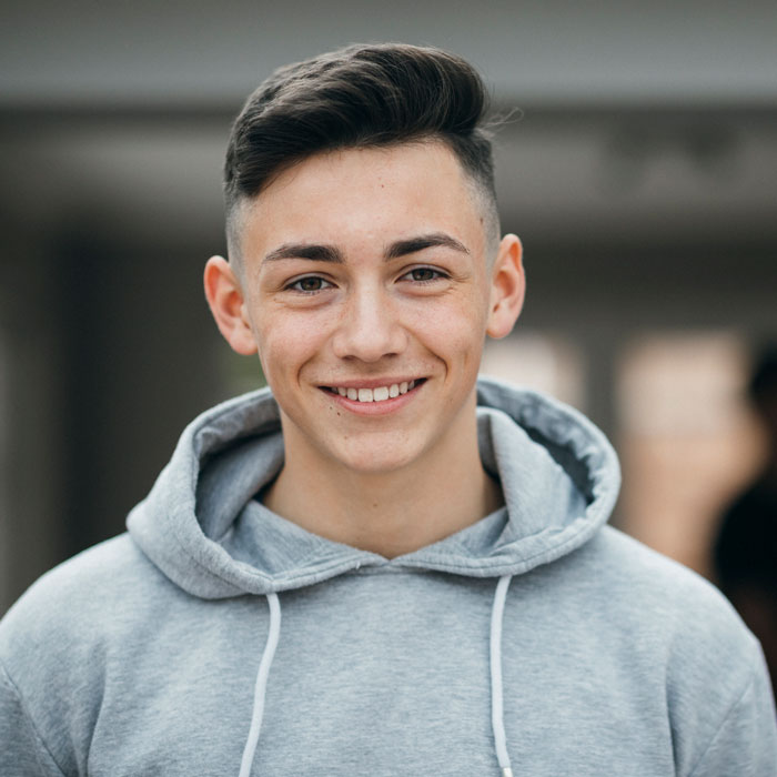young adult man in gray hoodie smiling