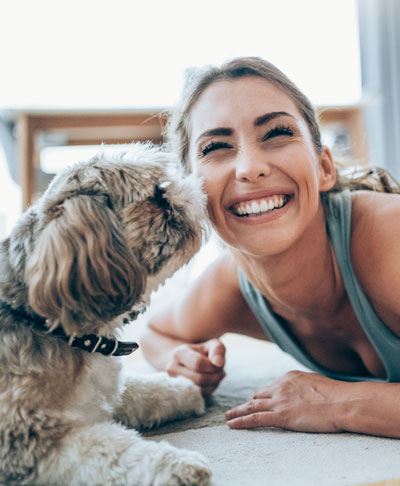 woman smiling while playing on floor with fluffy dog
