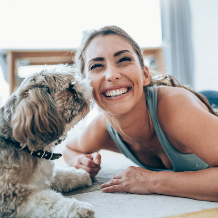 woman smiling while playing on floor with fluffy dog